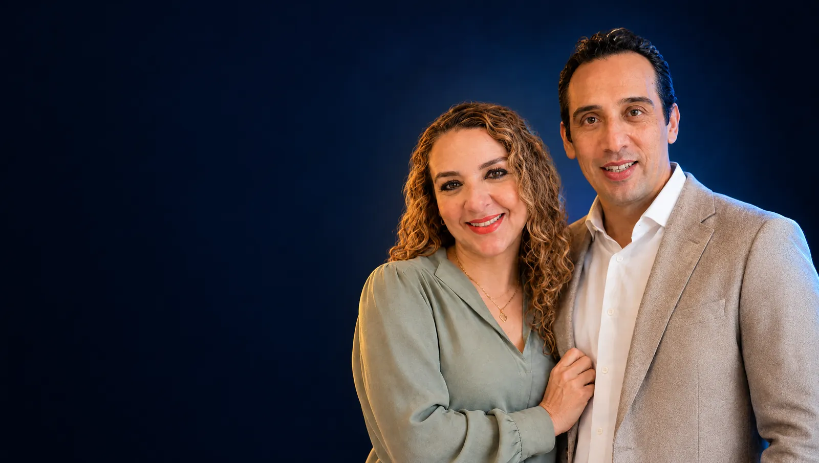 Alicia y Hugo, juntos y sonrientes, frente a un fondo azul noche